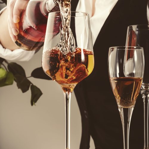 Sommelier pouring rose wine into glass at wine tasting in winery, bar or restaurant. White background